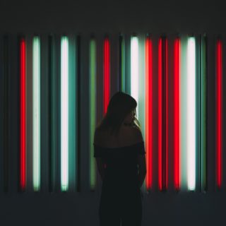 A woman stands in front of neon tubes
