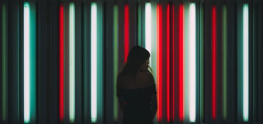 A woman stands in front of neon tubes